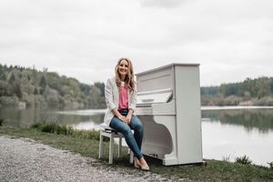 Judith Mutschler am weißen Klavier - vor einem See fotografiert